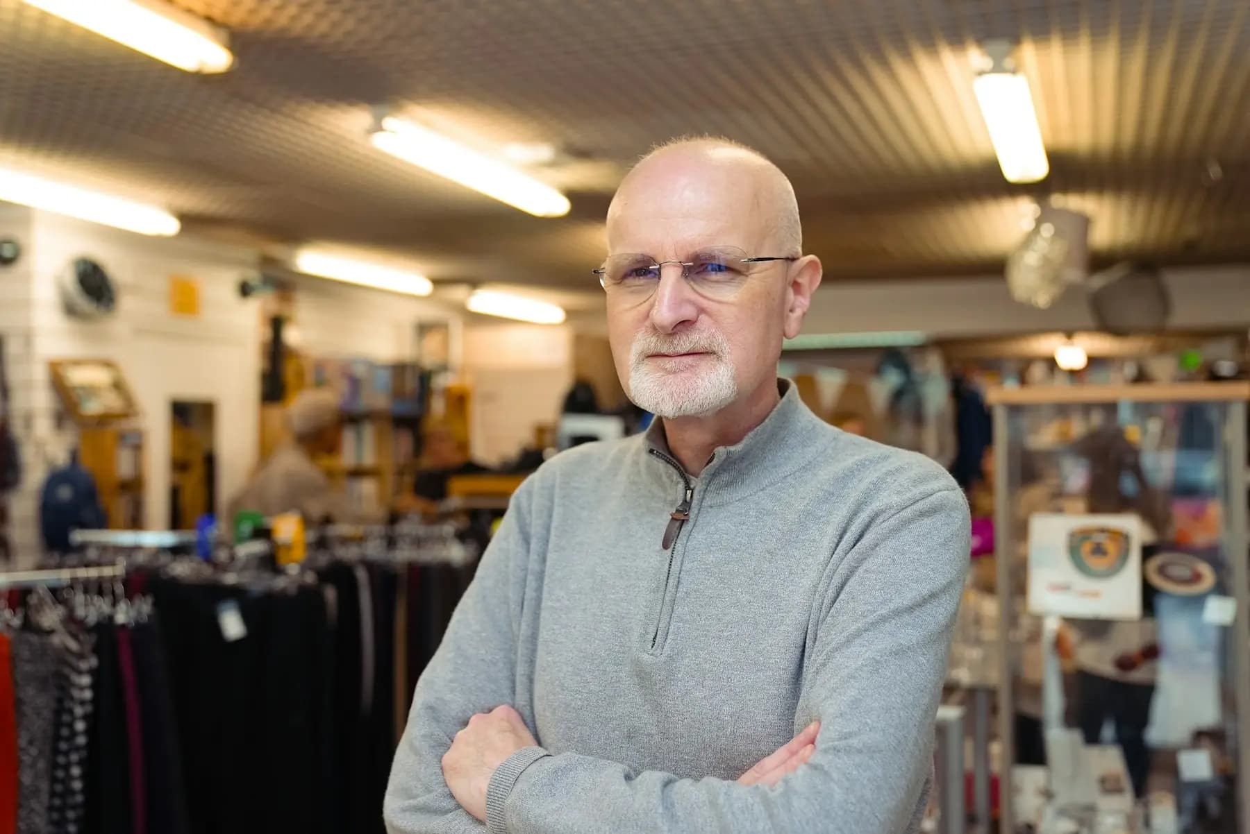 A local shop owner standing with his arms crossed in his store